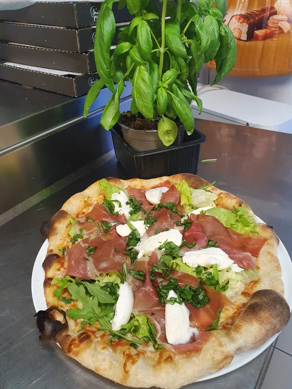 Pizza jambon cru et basilic frais, croûte levée sortie du four à bois.